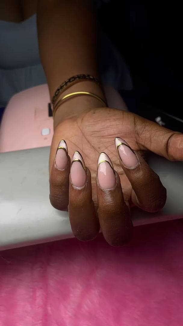 Almond-shaped nails with a gold-lined French tip by QNB